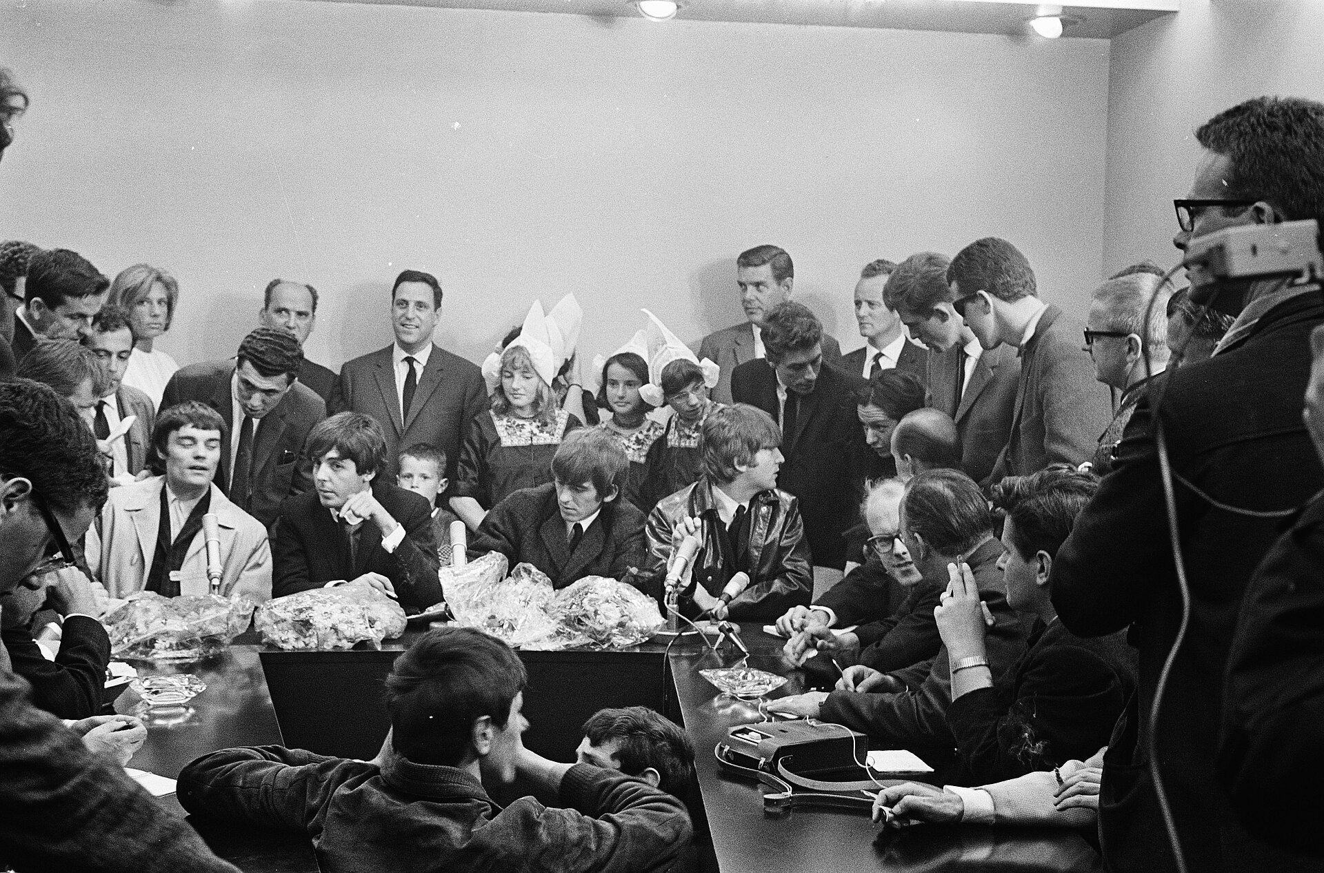 The Beatles seated at a press conference table after landing at Schiphol Airport in June 1964