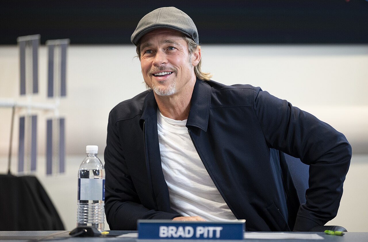Brad Pitt speaking into a microphone at NASA Headquarters during a live call with the International Space Station in 2019