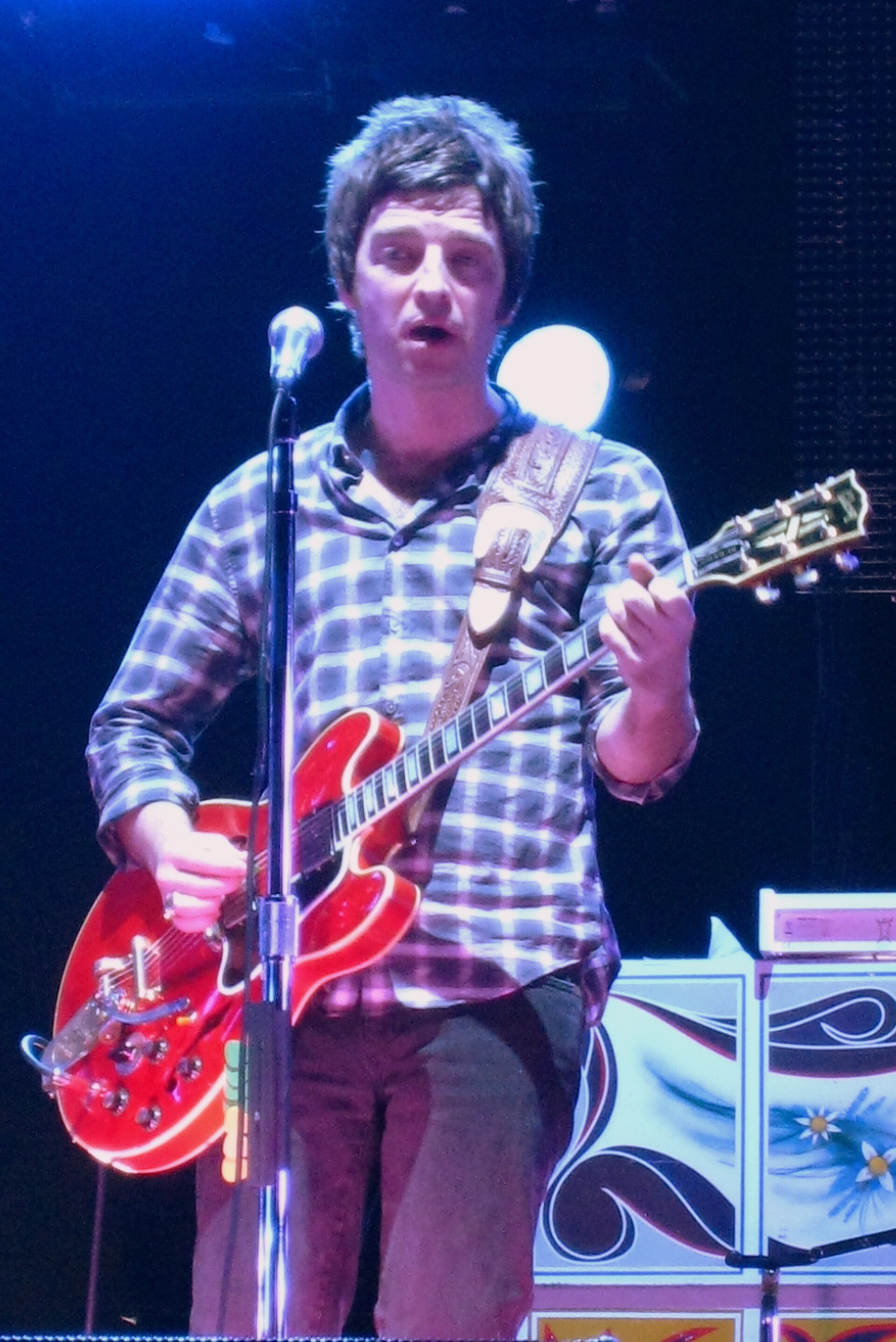 Noel Gallagher playing guitar and singing on stage in 2008